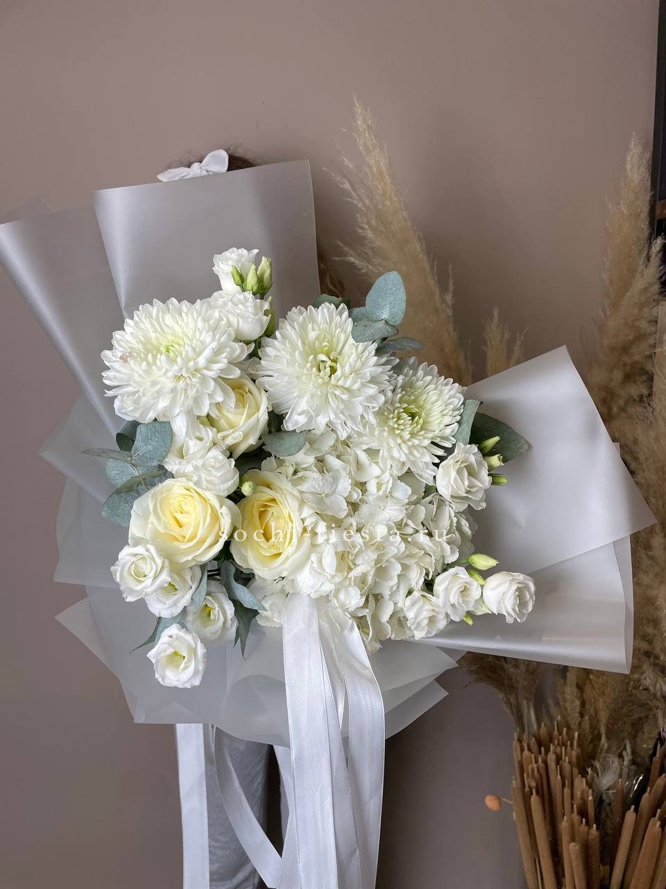 флорист небольшого города собирает авторский сборный букет с розами и сезонными цветами